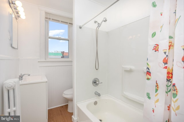 bathroom featuring radiator, wood finished floors, wainscoting, toilet, and shower / tub combo