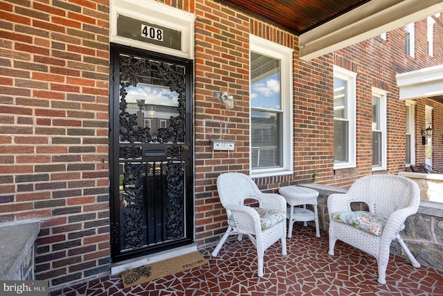 entrance to property featuring brick siding and a porch