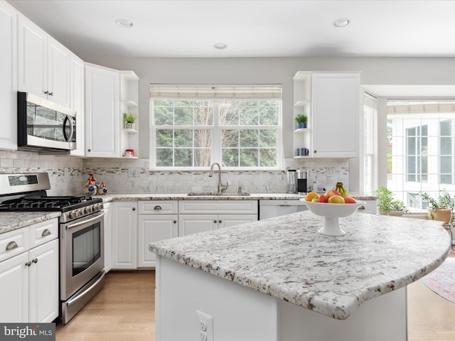 kitchen with tasteful backsplash, white cabinets, open shelves, a sink, and appliances with stainless steel finishes