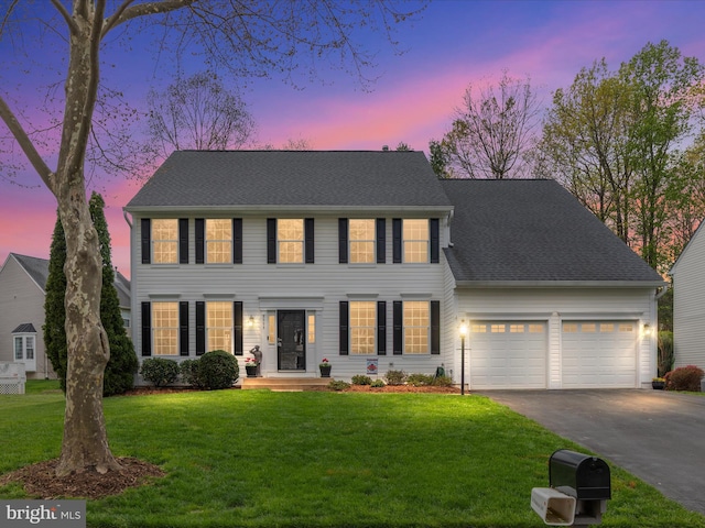 colonial inspired home with aphalt driveway, roof with shingles, a front lawn, and an attached garage