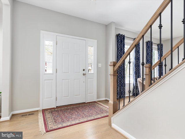 entryway featuring visible vents, baseboards, stairway, and wood finished floors