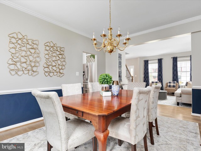 dining room featuring ornamental molding, a notable chandelier, wood finished floors, and stairs