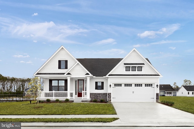 view of front facade featuring a front yard, a shingled roof, a porch, stone siding, and concrete driveway