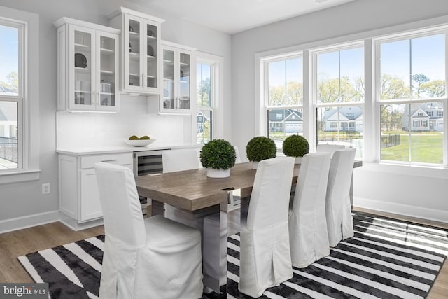dining room featuring light wood-style flooring, baseboards, and beverage cooler