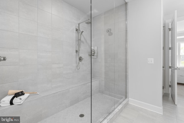 bathroom with tile patterned floors, baseboards, and a tile shower