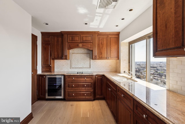 kitchen with visible vents, a sink, wine cooler, light wood finished floors, and backsplash