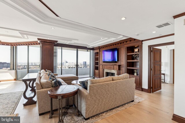 living room featuring ornamental molding, recessed lighting, light wood-style floors, visible vents, and a premium fireplace