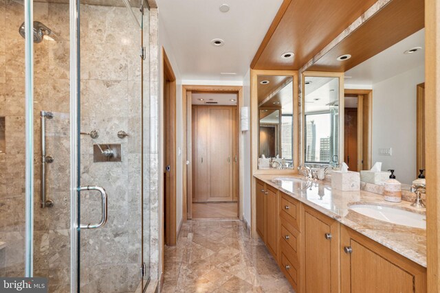 bathroom featuring double vanity, marble finish floor, a sink, and a stall shower