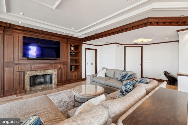 living area with light wood-style floors, crown molding, a fireplace, recessed lighting, and built in shelves