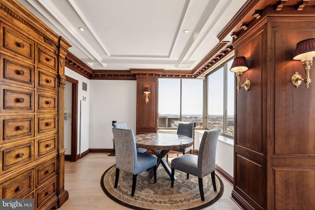 dining space with light wood-type flooring, baseboards, and a raised ceiling