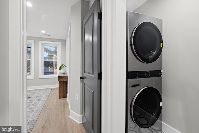washroom featuring stacked washer / drying machine, light wood finished floors, baseboards, and recessed lighting