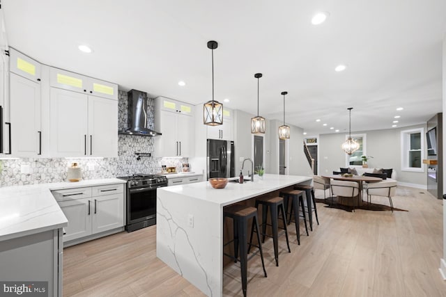 kitchen featuring appliances with stainless steel finishes, wall chimney range hood, decorative backsplash, light wood-type flooring, and recessed lighting