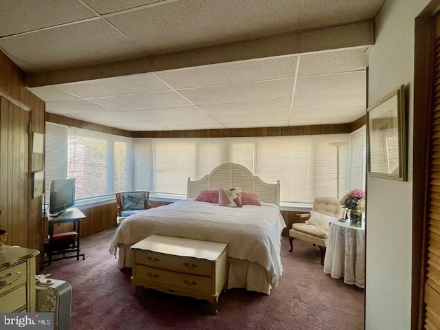 bedroom featuring wood walls, a drop ceiling, and carpet