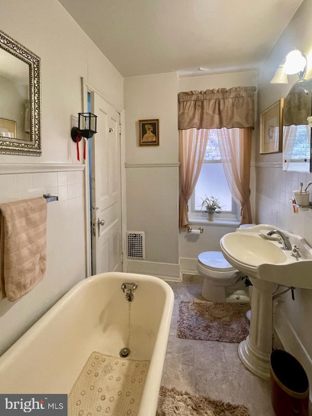 full bathroom with a soaking tub, visible vents, toilet, tile walls, and tile patterned floors