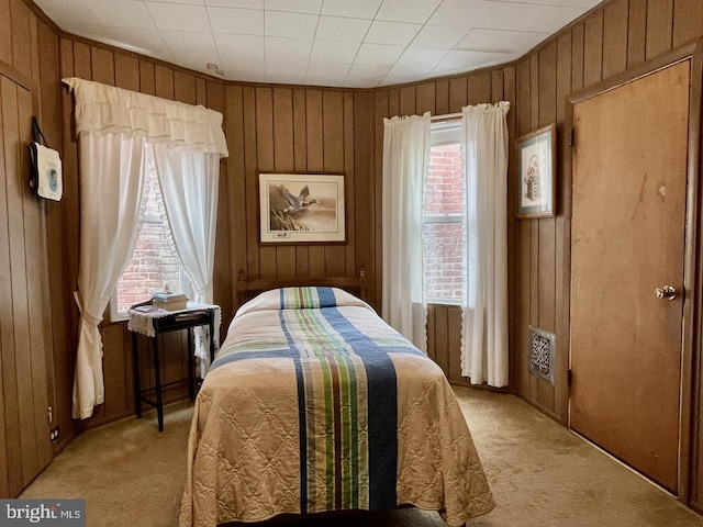 bedroom featuring light carpet and wooden walls