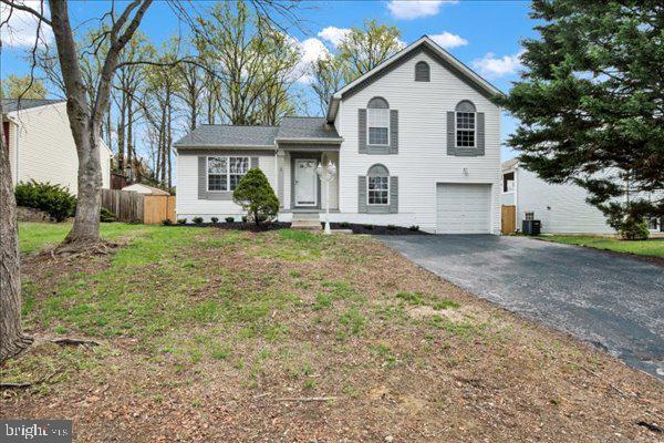 6135 Rainbow Dr, Elkridge, MD 21075 - tri-level home with central AC unit, a garage, fence, a front lawn, and driveway