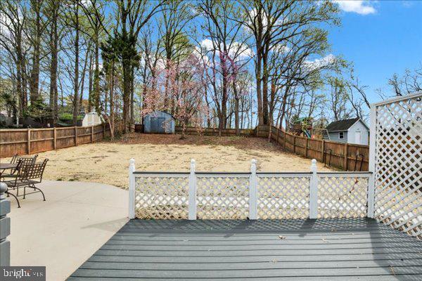 6135 Rainbow Dr, Elkridge, MD 21075 - deck with a fenced backyard, a storage shed, and an outbuilding