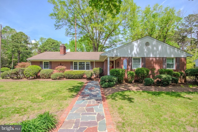 single story home with brick siding, a chimney, and a front yard
