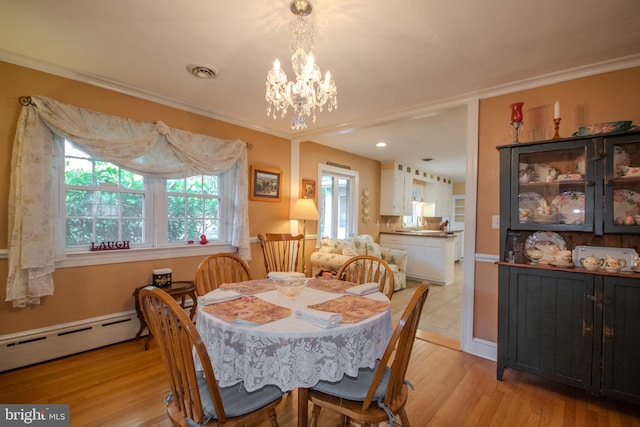 dining area with visible vents, crown molding, light wood-type flooring, a baseboard radiator, and a notable chandelier