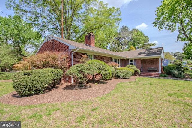 ranch-style home featuring brick siding, a front lawn, and a chimney