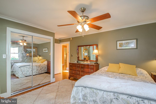 bedroom with crown molding, a ceiling fan, baseboards, wood finished floors, and a closet
