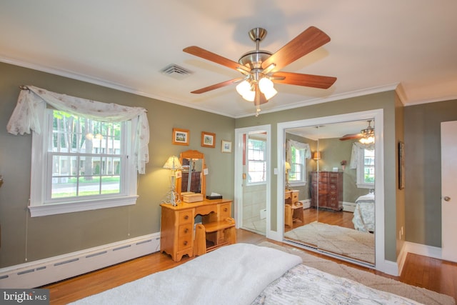bedroom featuring visible vents, ornamental molding, baseboard heating, and wood finished floors