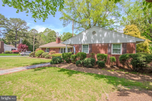 single story home featuring brick siding, a chimney, and a front lawn