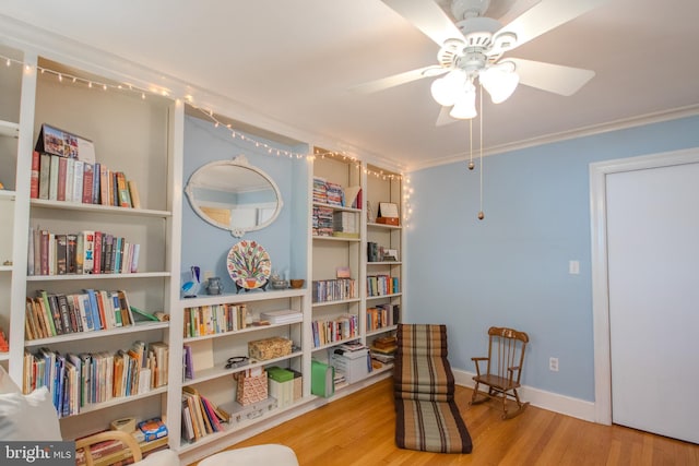 living area with crown molding, baseboards, ceiling fan, and wood finished floors