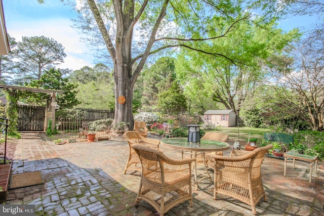 view of patio featuring an outdoor structure, fence, a storage shed, and outdoor dining space