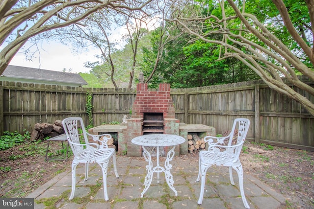 view of patio / terrace with a fenced backyard and an outdoor brick fireplace