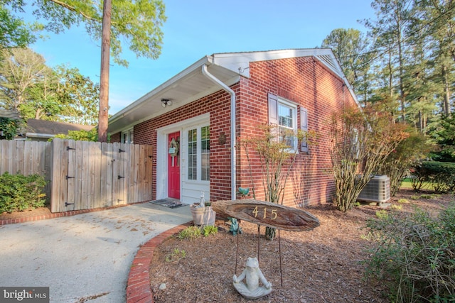 view of front facade with fence, a gate, cooling unit, and brick siding