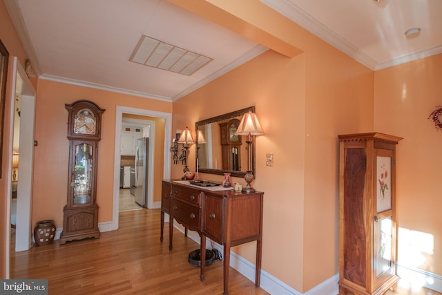 hallway with baseboards, ornamental molding, wood finished floors, and visible vents