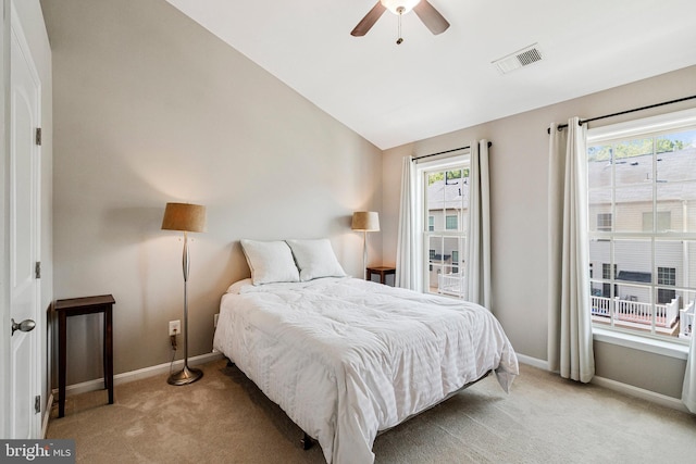 bedroom with light colored carpet, a ceiling fan, baseboards, vaulted ceiling, and visible vents