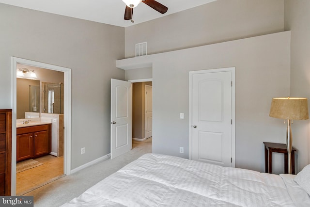 bedroom with visible vents, light colored carpet, a sink, a high ceiling, and ensuite bath