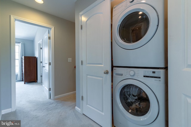 laundry area with laundry area, stacked washer and dryer, baseboards, and light carpet