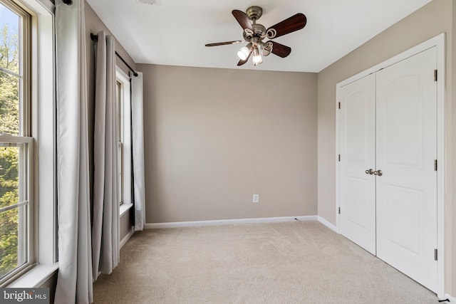 unfurnished bedroom with baseboards, light carpet, multiple windows, and a closet
