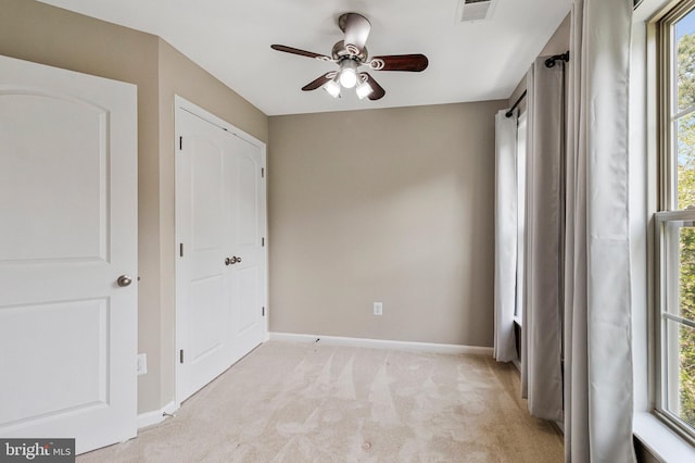 unfurnished bedroom featuring baseboards, visible vents, a ceiling fan, and light colored carpet