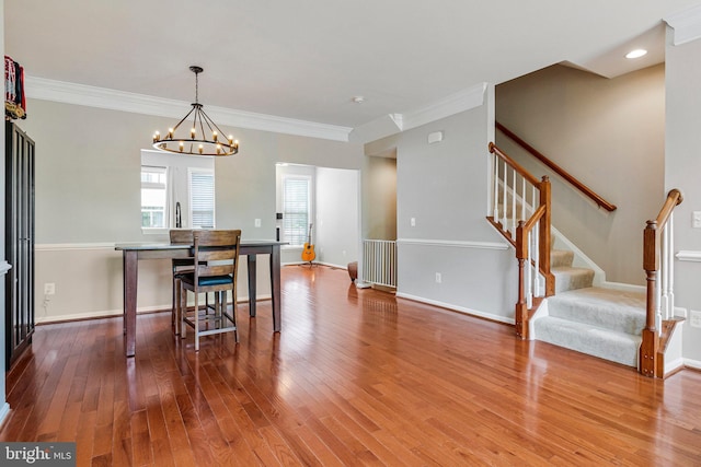 dining room featuring crown molding, wood finished floors, stairway, baseboards, and an inviting chandelier