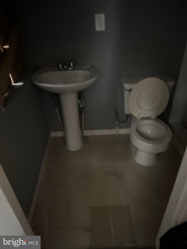 bathroom featuring toilet, tile patterned floors, and baseboards