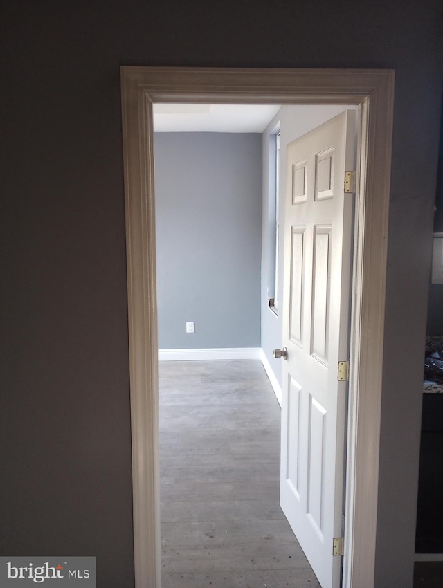 corridor featuring baseboards and wood finished floors