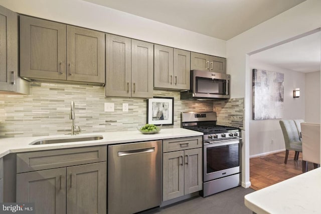 kitchen with a sink, backsplash, light countertops, and appliances with stainless steel finishes