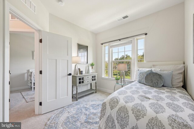 bedroom with visible vents, baseboards, and light carpet