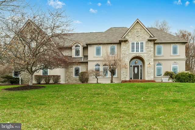 view of front facade with stucco siding, stone siding, and a front lawn