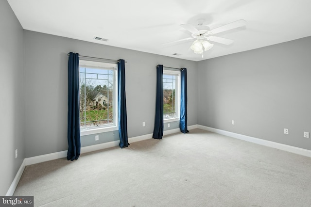 spare room featuring light carpet, baseboards, a ceiling fan, and visible vents