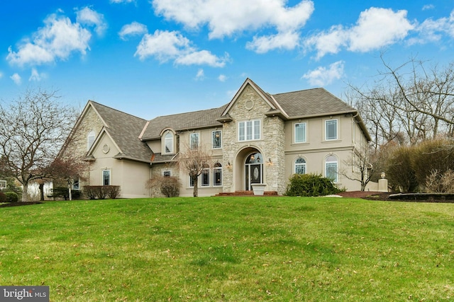 view of front of house featuring a shingled roof, stucco siding, stone siding, and a front yard