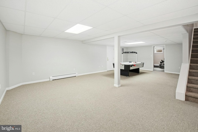 finished basement featuring a drop ceiling, stairway, carpet flooring, and a baseboard heating unit