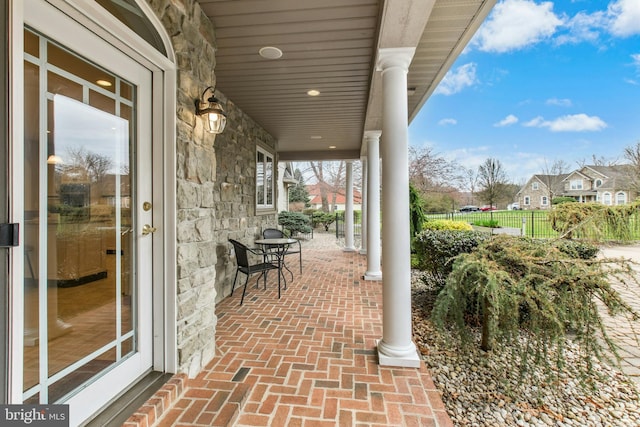 view of patio featuring a residential view, covered porch, and fence