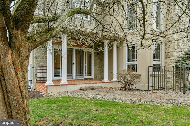 view of exterior entry featuring stone siding and covered porch