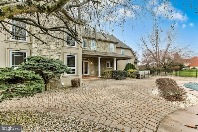 view of front of house with fence, stone siding, and stucco siding