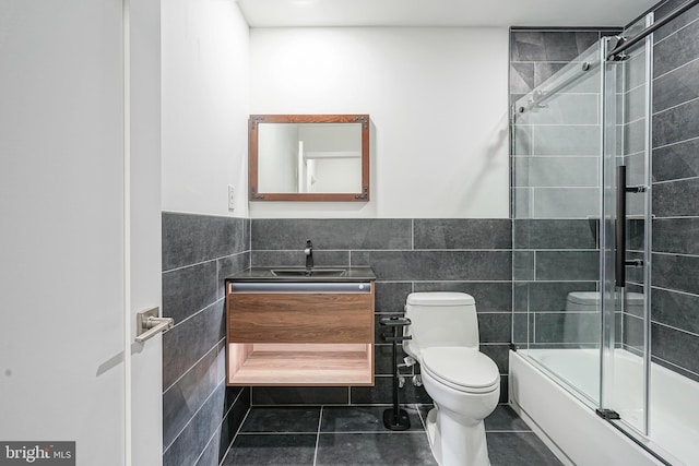 1143 Tasker St, Philadelphia, PA 19148 - bathroom with tile patterned floors, bath / shower combo with glass door, toilet, tile walls, and vanity